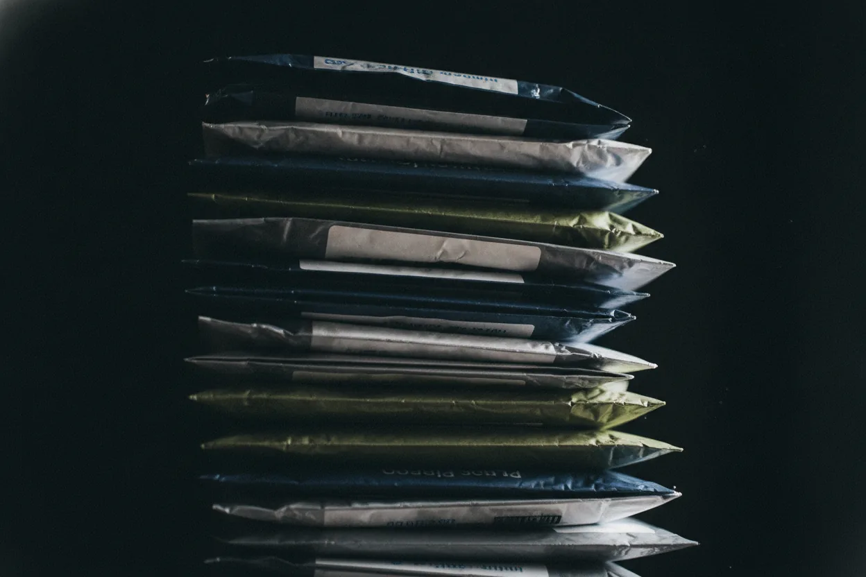 A detailed close-up of a stack of poly mailers on a dark surface, emphasized by dramatic lighting.