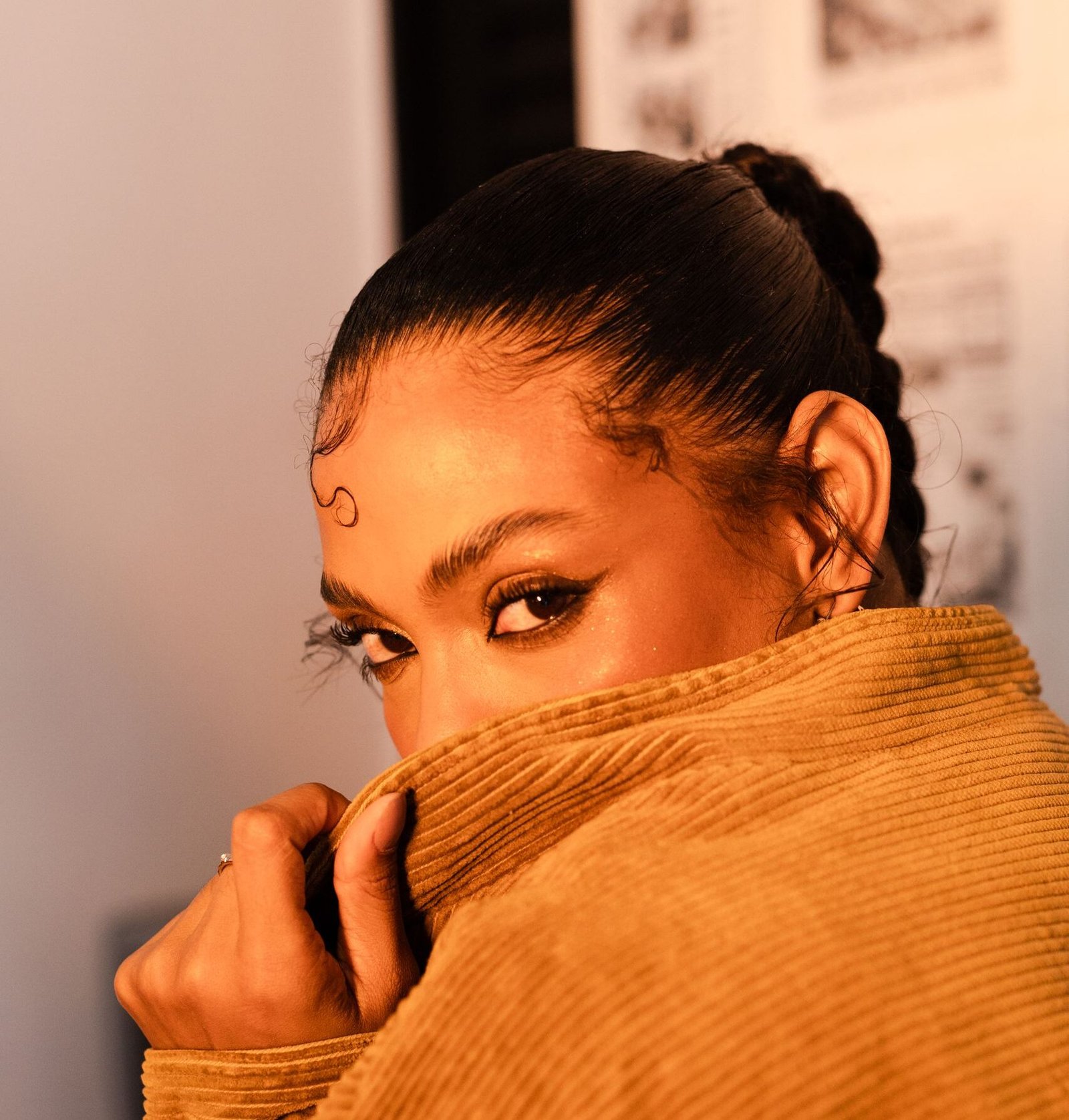 Striking portrait of a woman in a corduroy jacket with warm lighting and mysterious gaze.
